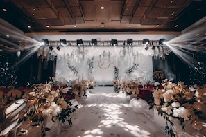 An indoor venue with a stage, floral arrangements, and seating for an event. - Yushan Hotel (Changshu)