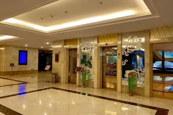 A hotel lobby with a marble floor, a reception desk, and decorative wall panels. - Yushan Hotel (Changshu)