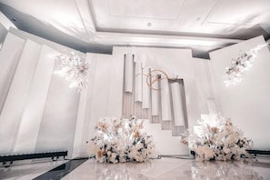 Un interior moderno con diseño minimalista, que presenta una estructura decorativa central, arreglos florales simétricos y un piso pulido.