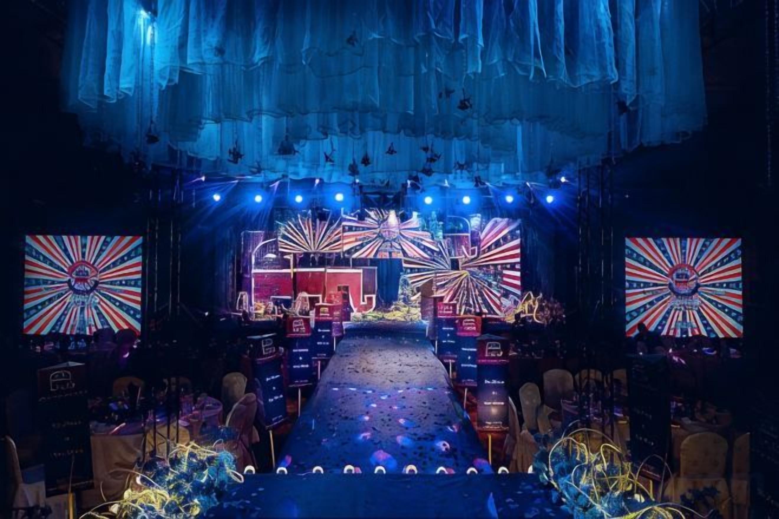 Un escenario con un fondo azul, un pasillo central y dos paneles decorativos grandes a cada lado.