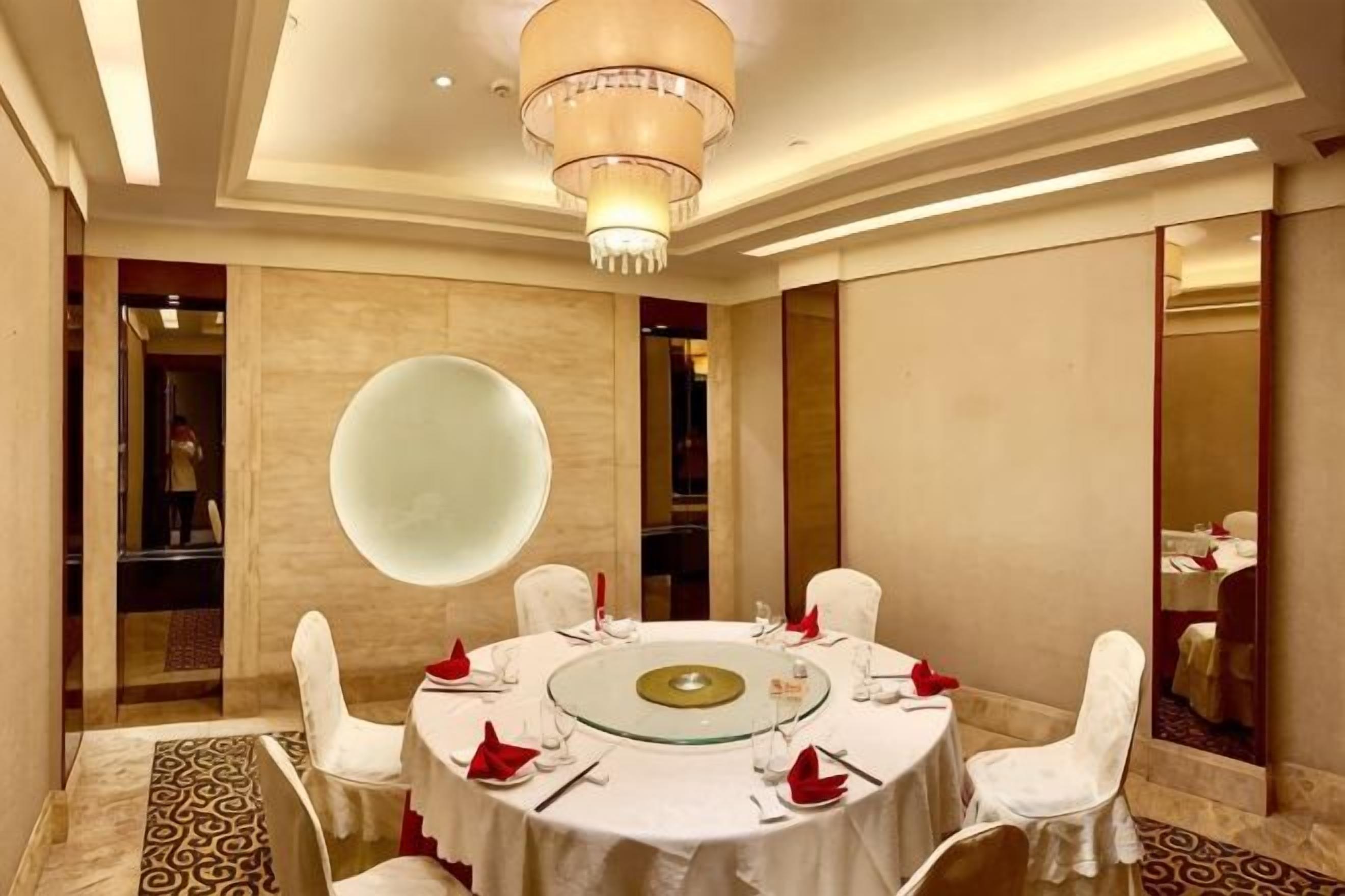 A round table with chairs, a chandelier, and a large mirror.