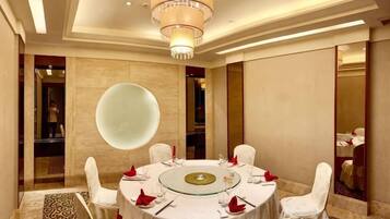 A round table with chairs, a chandelier, and a large mirror.