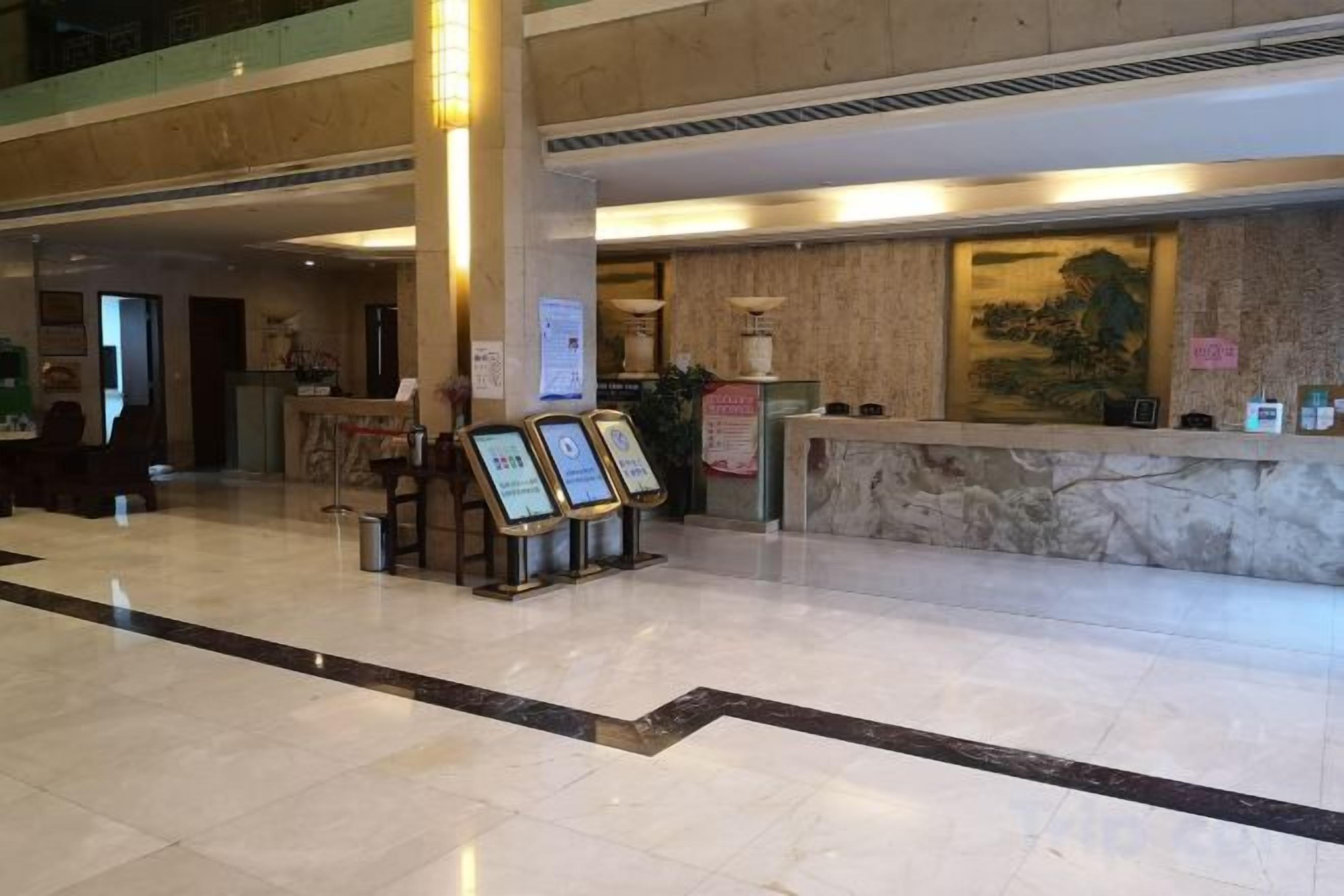 Un vestíbulo de hotel con una mesa de recepción, señalización informativa y un cuadro grande en la pared.