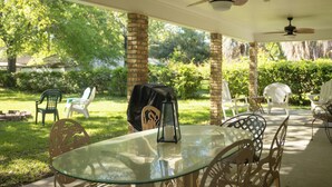 A covered patio with a glass table, wicker chairs, and a ceiling fan. - 3BR/2.5BA close to Beach, Casinos & Downtown Ocean Springs! Shorebound (Ocean Springs)