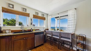 Uma cozinha com armários de madeira, lava-louças e uma área de refeições com mesa e cadeiras.