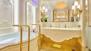A luxurious bathroom with a large bathtub, a vanity with a mirror, and gold fixtures.