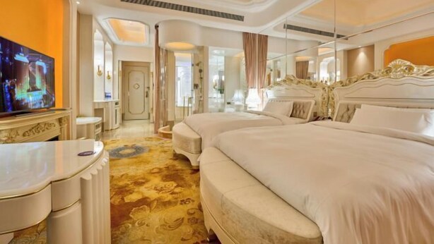 Una habitación de hotel con una cama grande, televisión, escritorio y espejo.