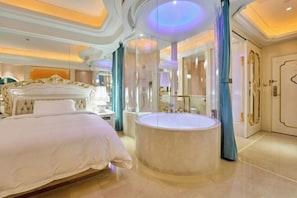 Une chambre à coucher luxueuse avec un grand lit, une baignoire ronde et un miroir.