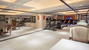 Un gimnasio con varias máquinas de ejercicio, una zona de recepción y un área de descanso con sillas.