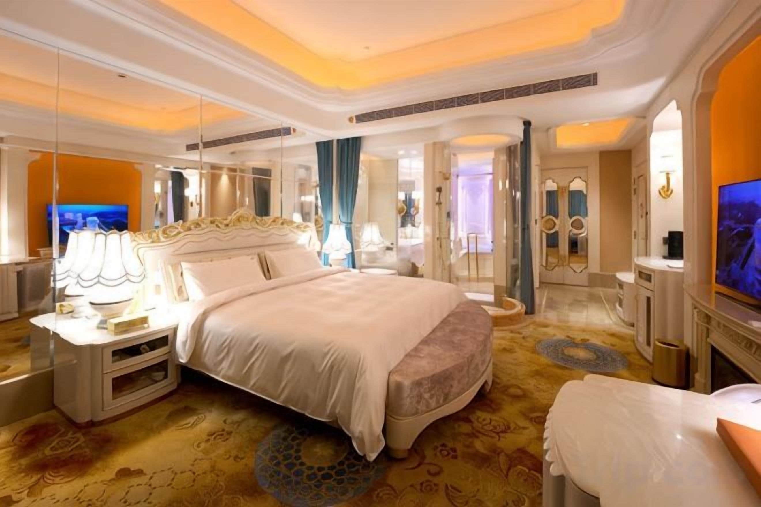 A spacious hotel room with a large bed, a television, and a bathroom with a mirror and sink.