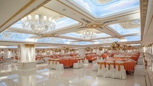Un amplio salón con mesas y sillas, candelabros y un alto techo con tragaluces.