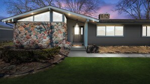 Et moderne hus med en stenfassade, en veranda og en velplejet græsplæne.