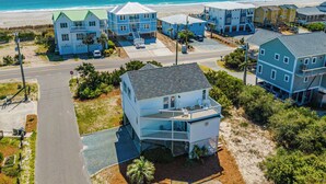 A coastal residential area with beachfront properties, including a house with a balcony and a view of the ocean. - The Channel Marker by Topsail Realty (Holly Ridge)