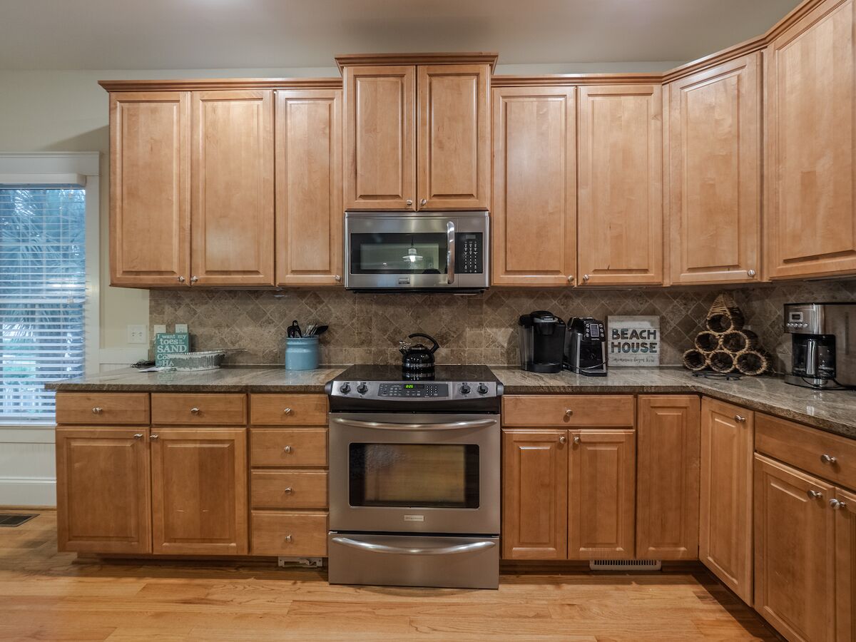 A kitchen with wooden cabinets, a stainless steel microwave, a gas stove, and a coffee maker.