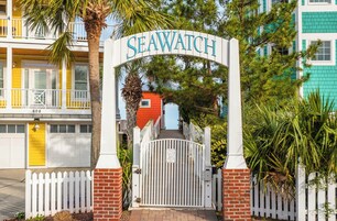Uma entrada com portão, uma placa com a inscrição 'SEAWATCH' e um muro de tijolos.