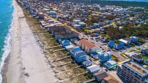 An aerial view of a coastal residential area with houses, a beach, and a pier. - Beach Breeze by Carolina Retreats (Carolina Beach)