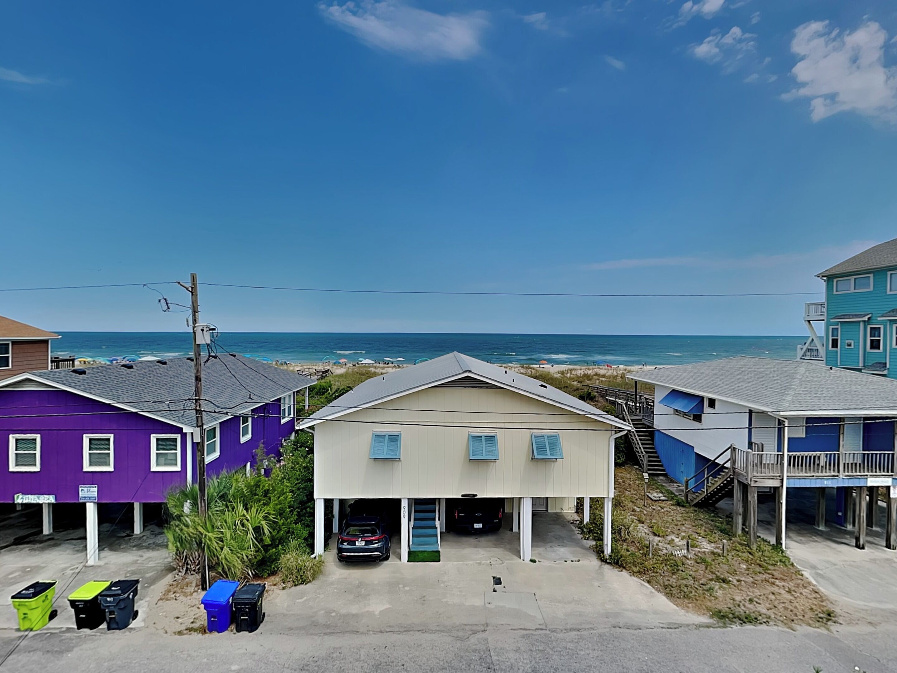 A coastal residential area with houses, a parking area, and a view of the beach and ocean.