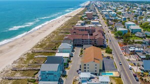 An aerial view of a coastal residential area with houses, a beach, and a road. - Beach Breeze by Carolina Retreats (Carolina Beach)