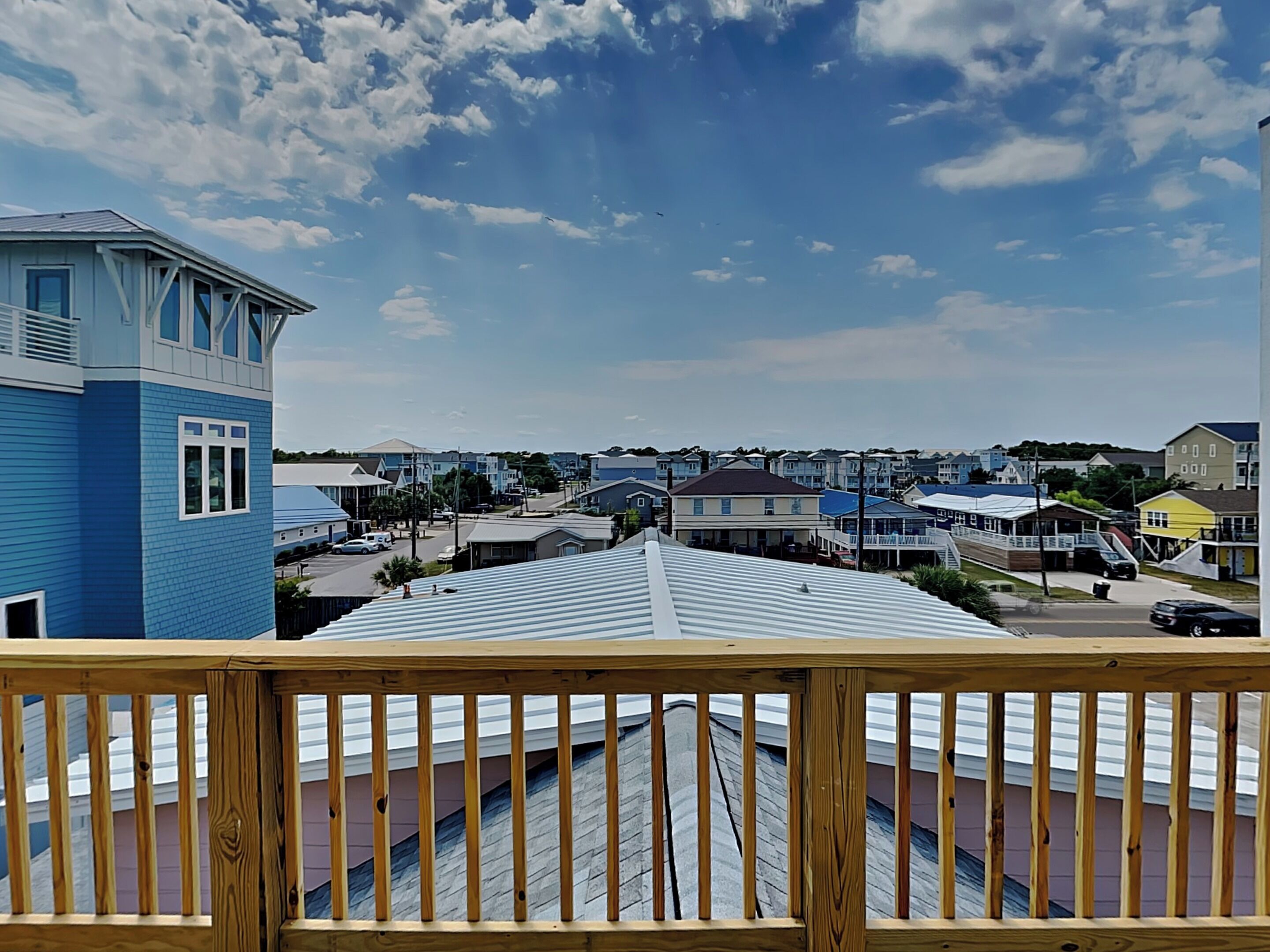 A residential neighborhood with houses, a blue building, and a wooden deck.