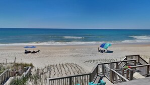 A beach with a wooden boardwalk leading to beach chairs and umbrellas. - Hailey's Hideaway by Topsail Realty (Holly Ridge)