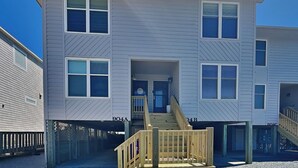 A multi-story building with a central staircase and a small porch area. - Hailey's Hideaway by Topsail Realty (Holly Ridge)