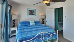 A bedroom with a bed, ceiling fan, and artwork on the wall. - Hailey's Hideaway by Topsail Realty (Holly Ridge)