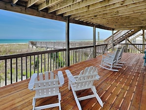 A wooden deck with white Adirondack chairs overlooking a beach. - Paradise Palms by Topsail Realty (Holly Ridge)