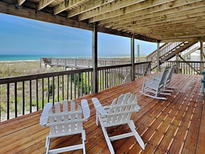 A wooden deck with white Adirondack chairs overlooking a beach. - Paradise Palms by Topsail Realty (Holly Ridge)