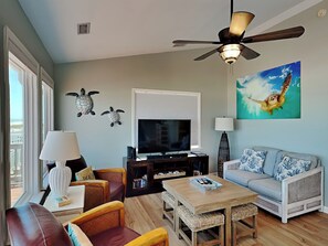 A living room with a television, sofa, chairs, and a ceiling fan. - Paradise Palms by Topsail Realty (Holly Ridge)