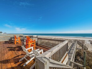 A wooden deck with beach chairs and a wooden railing overlooking a sandy beach and ocean. - Paradise Palms by Topsail Realty (Holly Ridge)