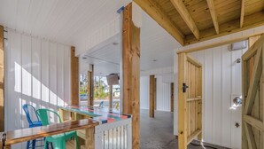 A spacious room with a wooden ceiling, a large window, and a view of the outside. - Jersey Blues by Carolina Retreats (Carolina Beach)