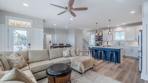 A spacious living room with a large sofa, a coffee table, and a ceiling fan. - Jersey Blues by Carolina Retreats (Carolina Beach)