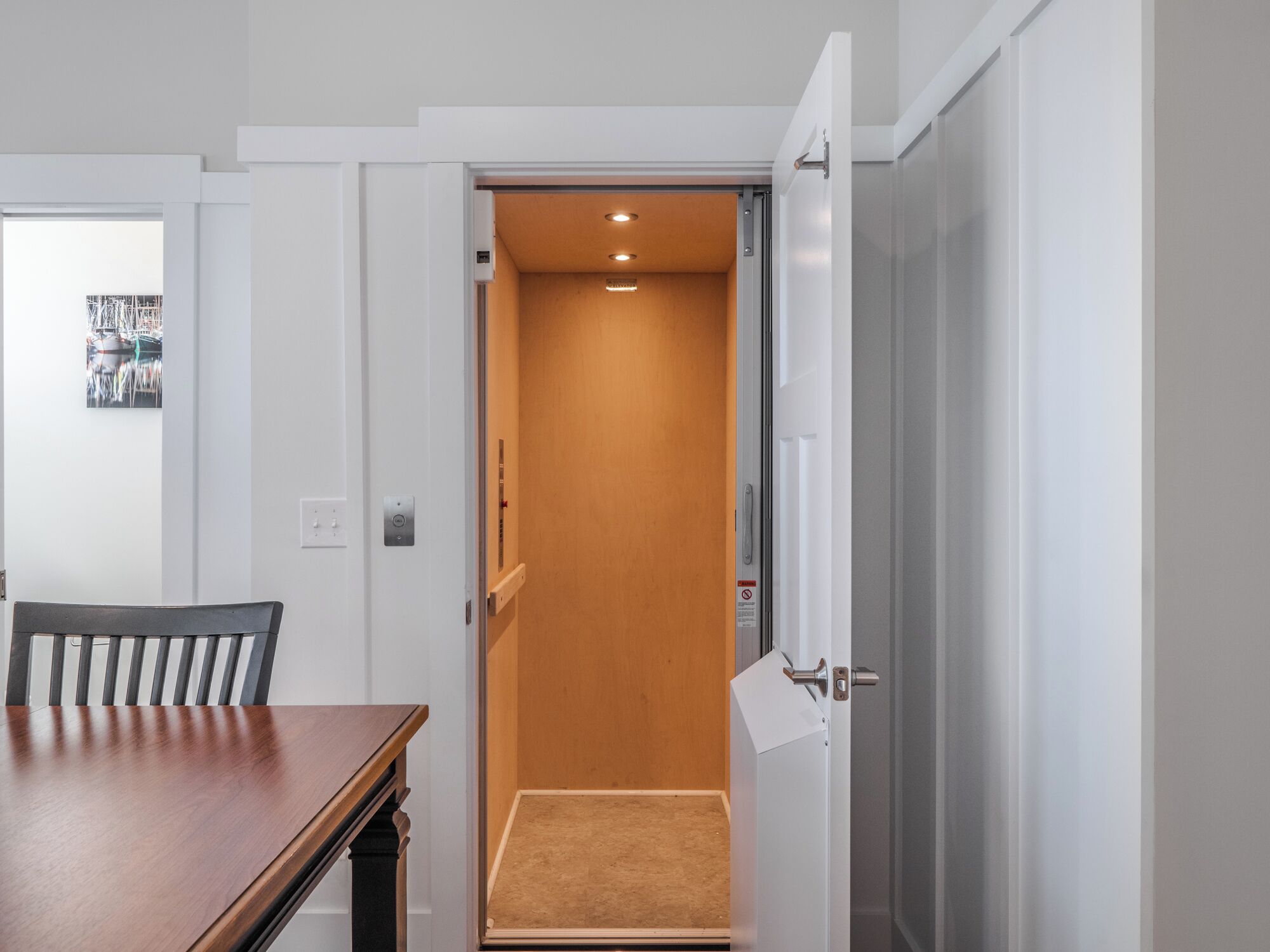 A narrow hallway with a wooden door leading to a room with a carpeted floor.
