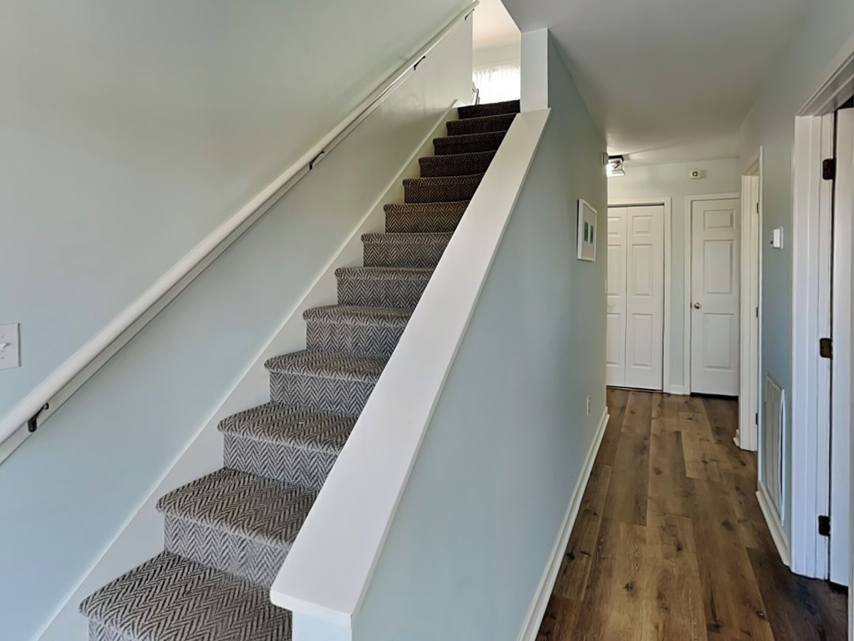 A staircase with patterned carpet leading to a landing.