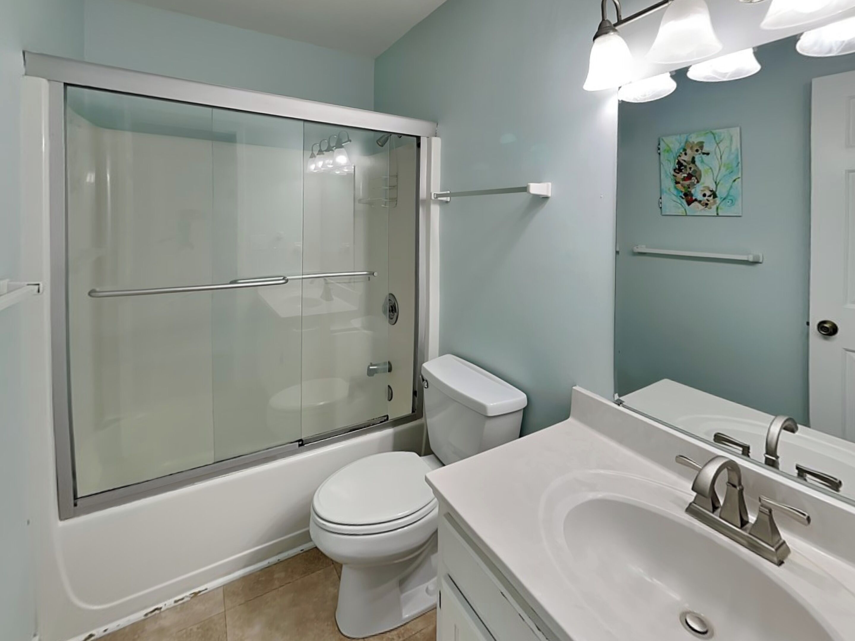 Un baño moderno con ducha de vidrio, inodoro y lavabo con espejo.