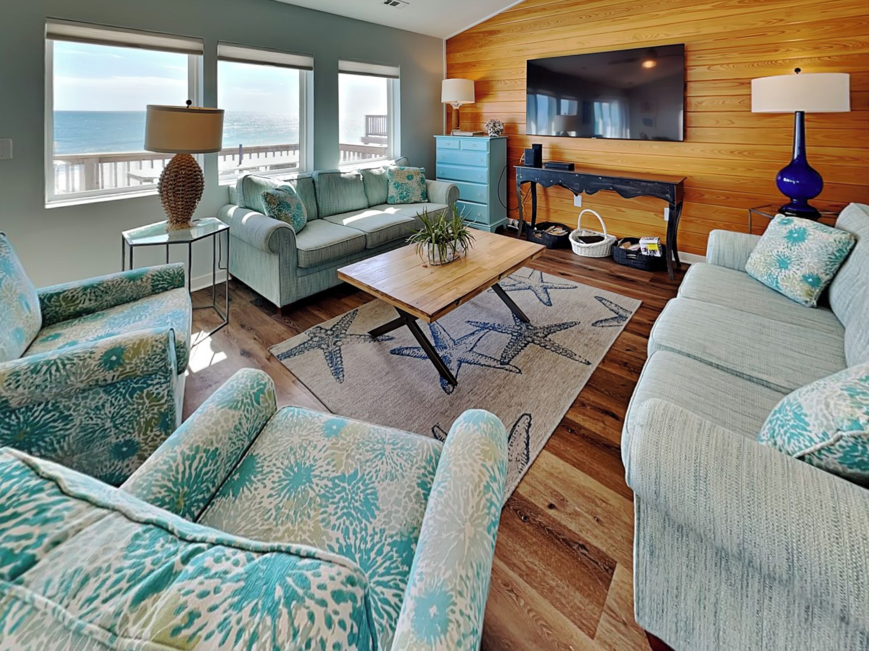 A living room with a sofa, armchairs, a coffee table, and a TV wall-mounted above a fireplace.