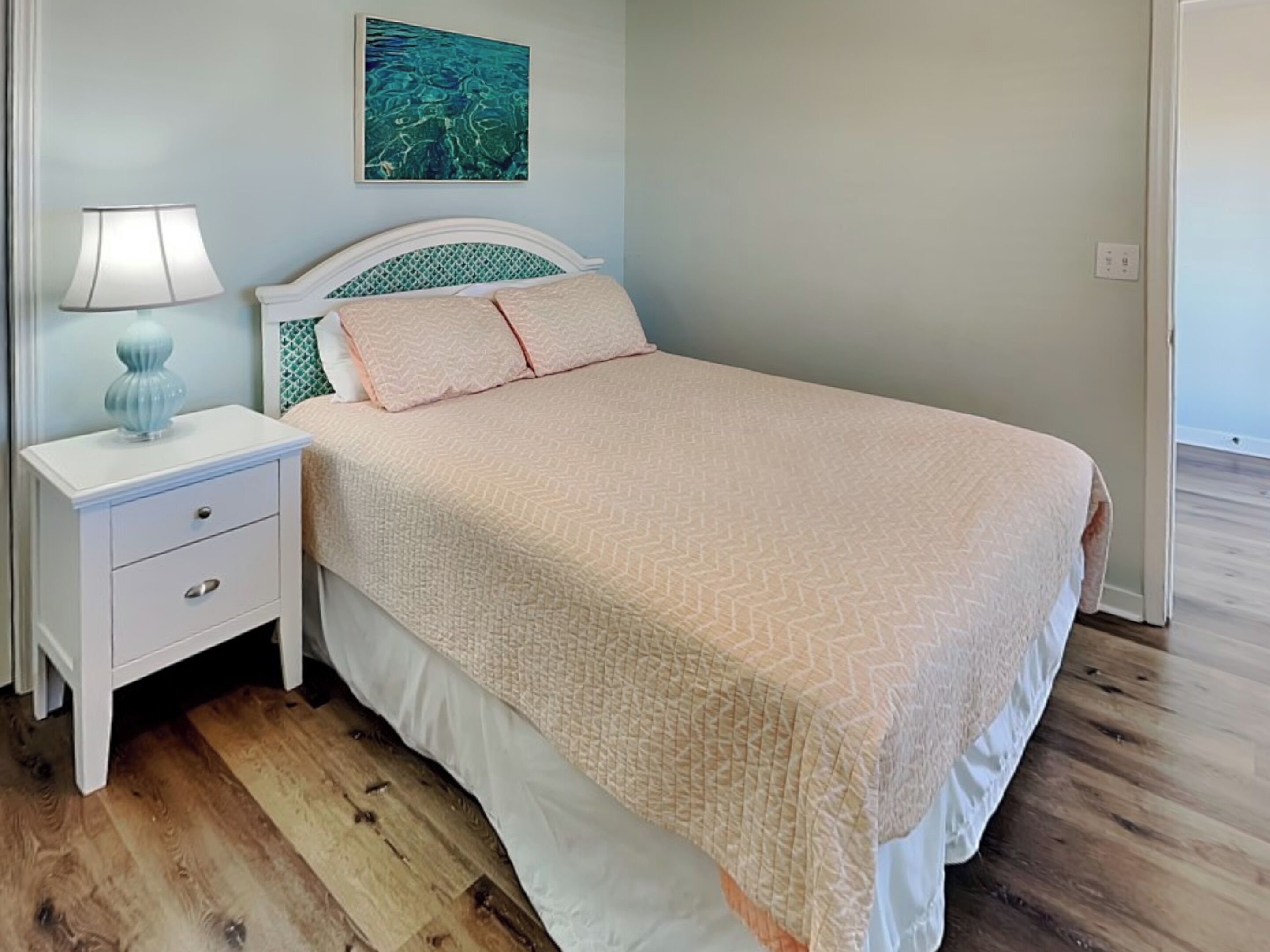 A neatly made bed with a patterned bedspread, a bedside lamp, and a small decorative item on the nightstand.