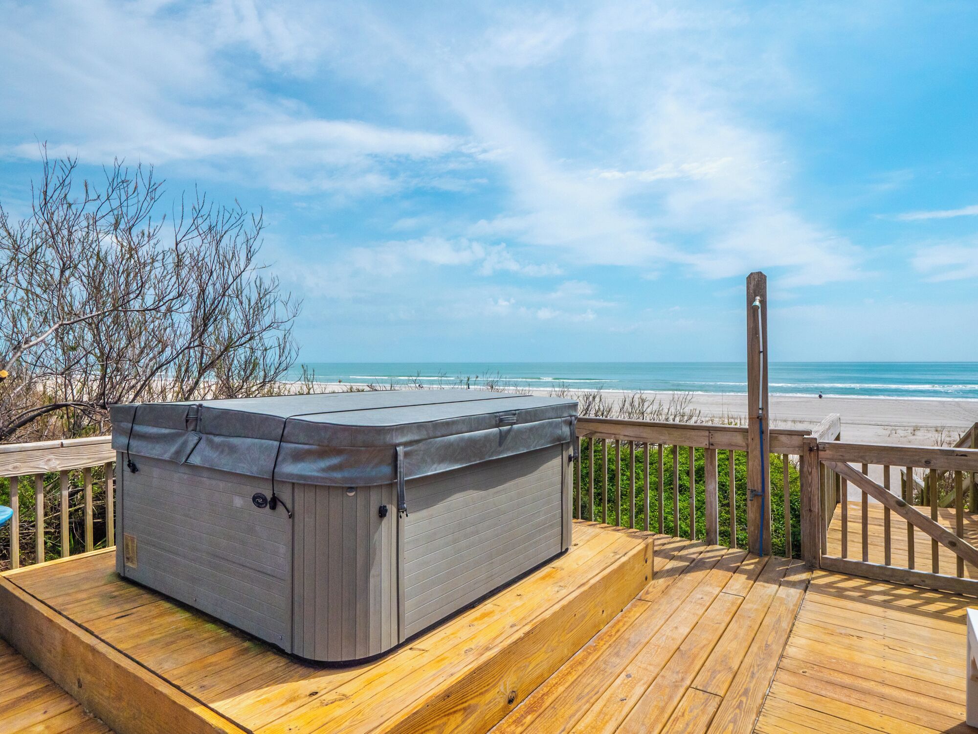 A hot tub on a wooden deck overlooking a beach.
