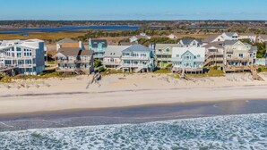 Un quartier résidentiel situé sur la côte, avec des propriétés en bord de mer, notamment des maisons dotées de balcons et offrant une vue sur l’eau.