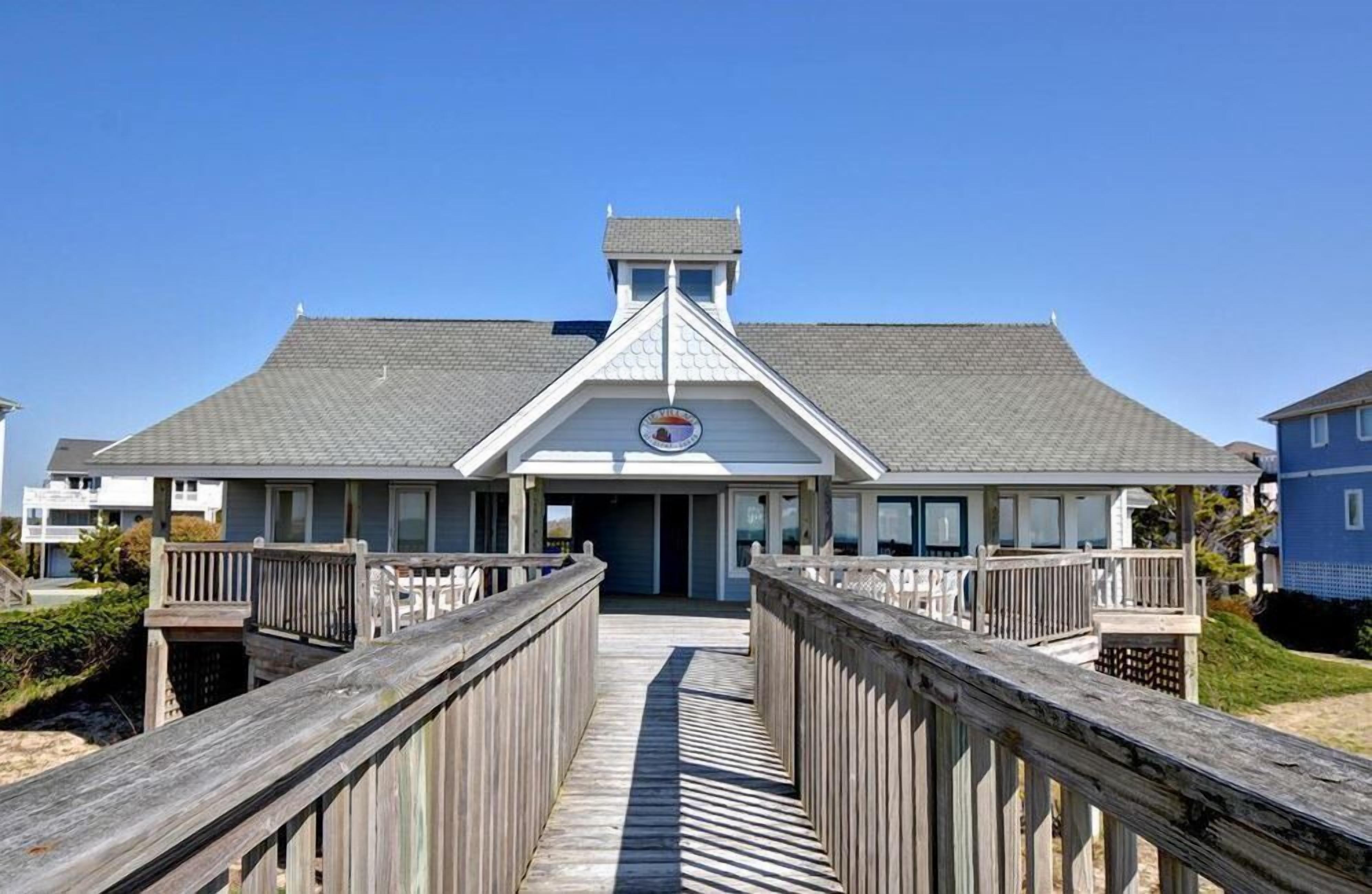 Un hôtel situé en bord de mer, doté d’une entrée centrale, d’une galerie couverte et offrant une vue sur l’océan.
