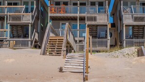 Une propriété située en bord de mer, comprenant des bâtiments à plusieurs étages, des balcons en bois et une plage de sable.