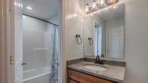 Un baño con bañera, lavamanos y espejo.
