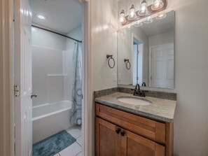 A bathroom with a bathtub, a sink, and a mirror. - Some Beach by Topsail Realty (Holly Ridge)