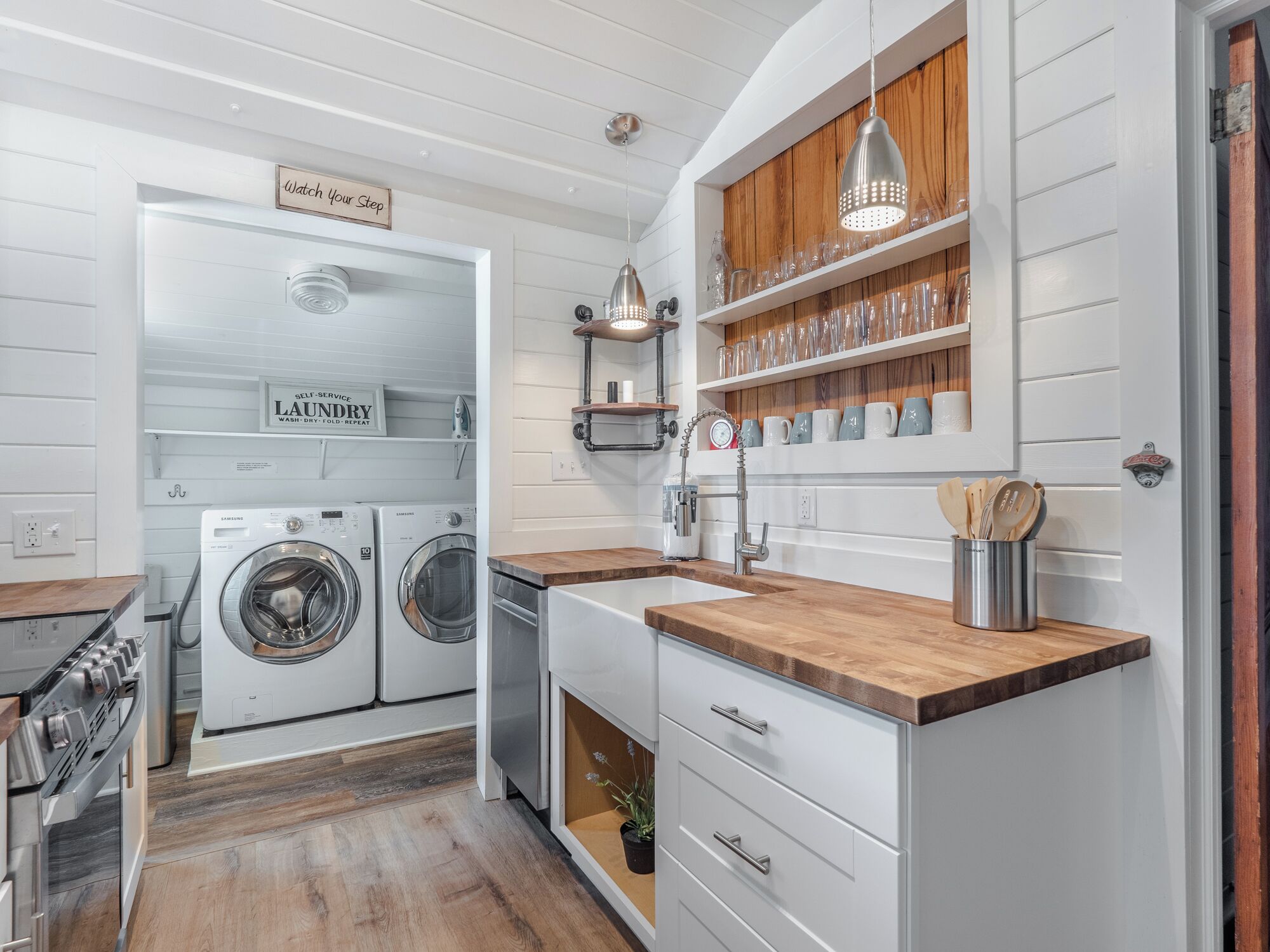 Une cuisine moderne dotée d’appareils électroménagers intégrés, de plans de travail en bois et d’un espace buanderie.
