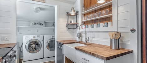Une cuisine moderne dotée d’appareils électroménagers intégrés, de plans de travail en bois et d’un espace buanderie.