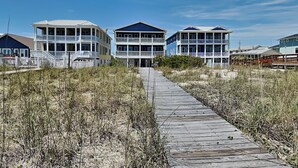 A beachfront property with a wooden boardwalk leading to a row of multi-story buildings with balconies. - No Worries in Paradise (Carolina Beach)