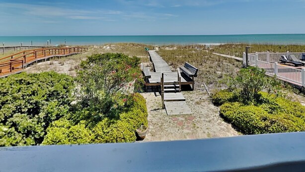 A beach view with a wooden boardwalk, benches, and a fence. - No Worries in Paradise (Carolina Beach)