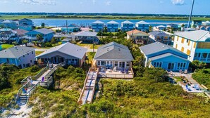 A coastal hotel with multiple blue buildings, a central structure with a covered patio, and a beach in the background.