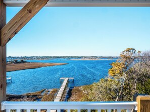 A wooden deck with a view of a calm body of water and a distant shoreline. - Happily Ever After by Topsail Realty (Holly Ridge)