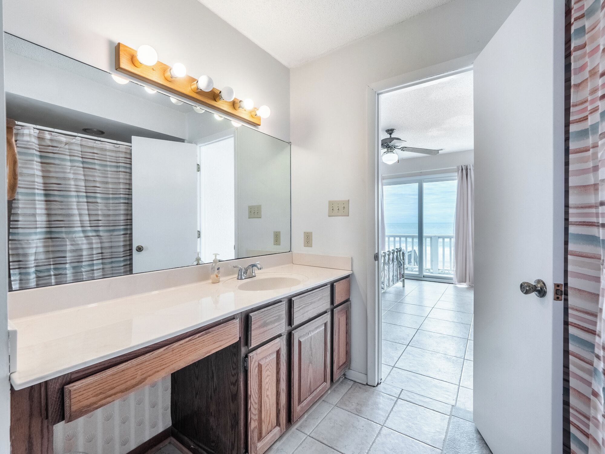 Un baño moderno con un espejo grande, tocador y vistas a un balcón.